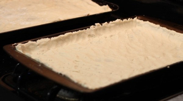 Add the flour and get busy with the dough. Place into the greased pans. It will continue to rise and you finish prepping, which is fine!