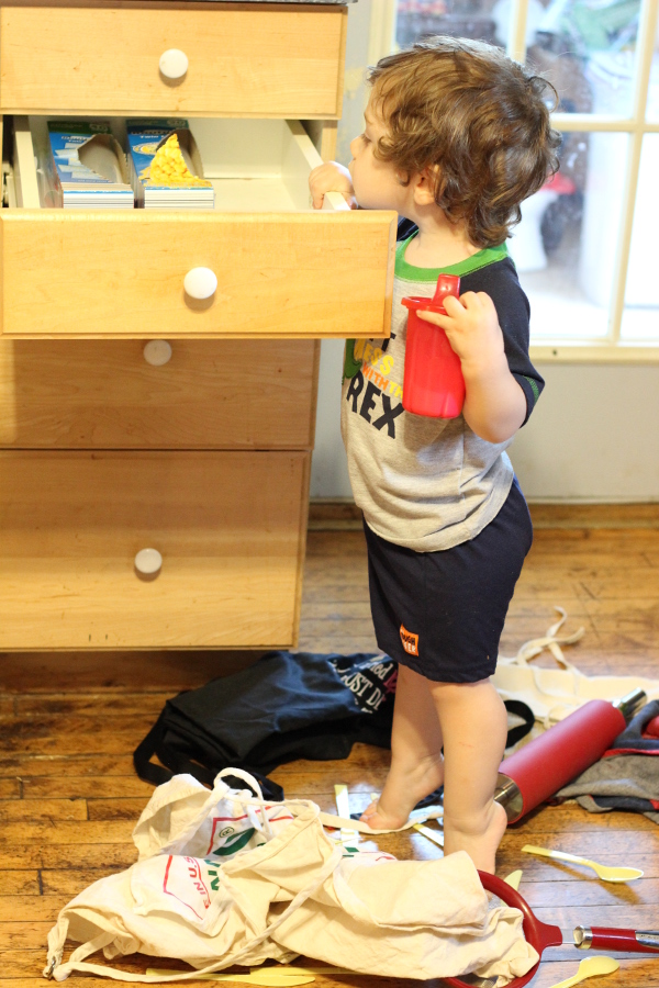 The baby decorated the floor with plastic forks, knives, spoons, aprons and rolling pins.